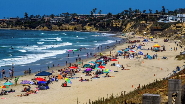 Ein überfüllter Strand mit Menschen, Sonnenschirmen und Zelten.