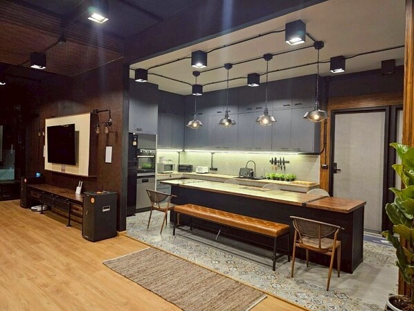 A modern kitchen with a central island, pendant lighting, and a seating area with benches.