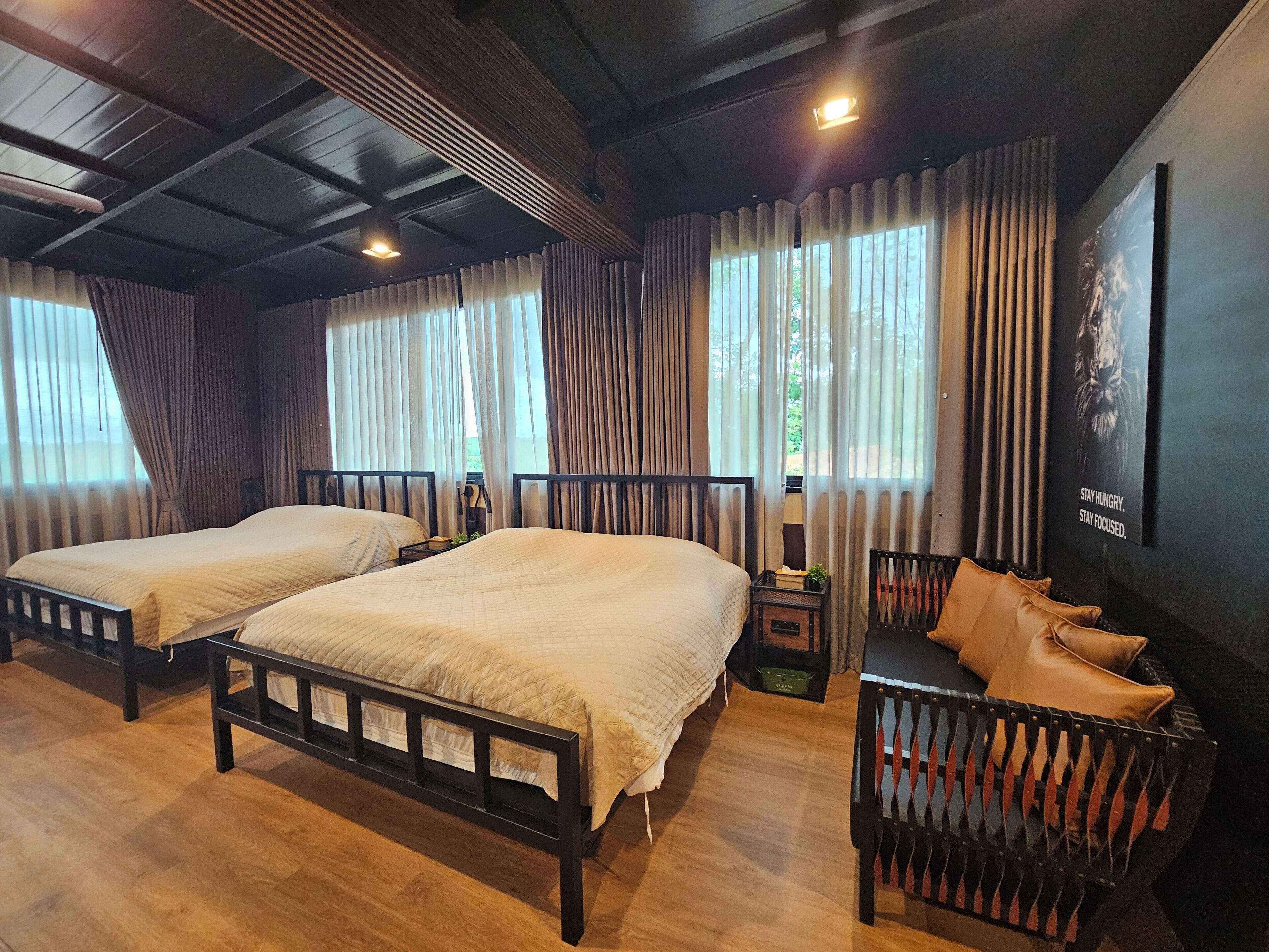 A hotel room with two beds, a small table, a chair, and a poster on the wall.