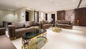 A modern living room with two sofas, a glass coffee table, and decorative vases. - Hotel Kingsway Continental Raipur (Raipur)
