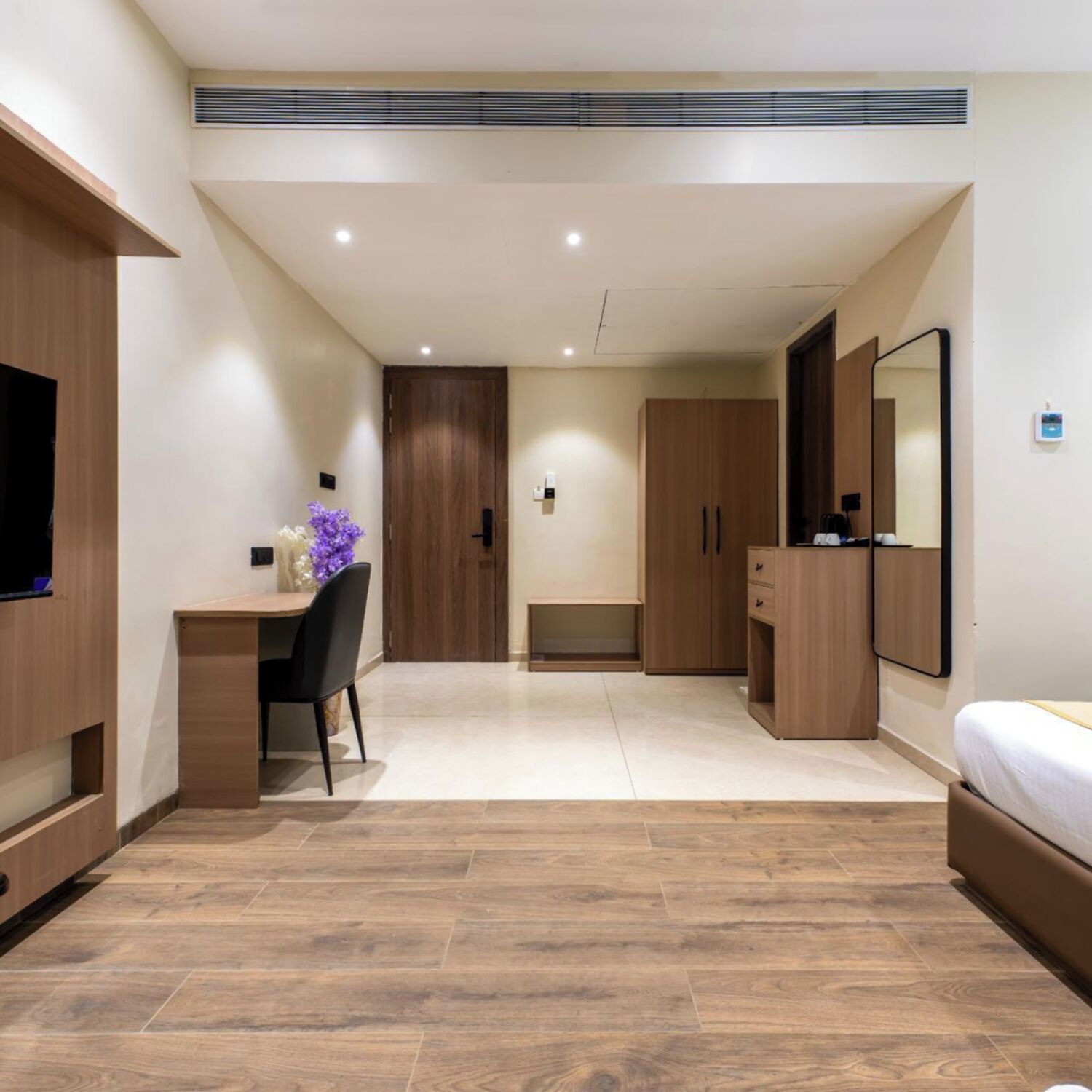 Un dormitorio moderno con un escritorio de madera, una silla, una cama, un armario y un televisor.