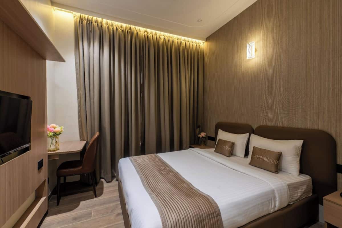 Habitación de hotel con cama, escritorio, silla y televisor.