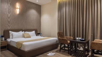 A hotel room with a large bed, two chairs, a small table, and a nightstand.