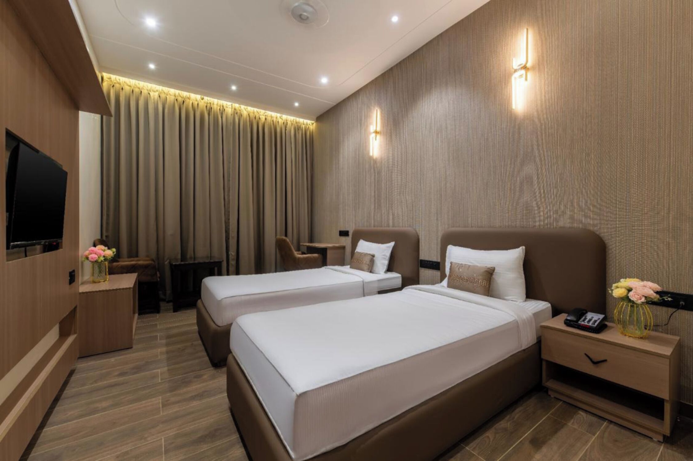 A hotel room with two beds, a TV, a desk, and a chair.
