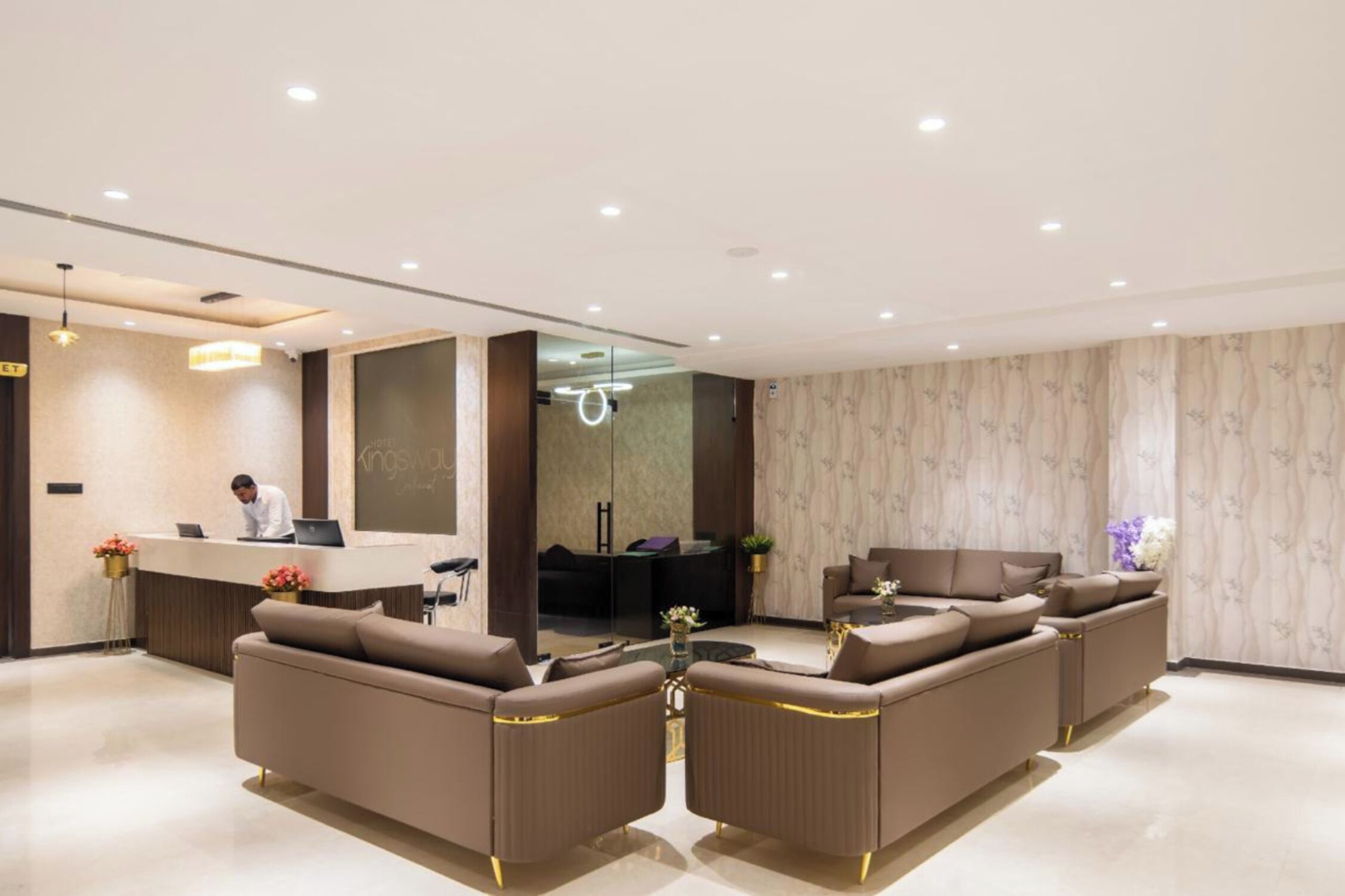 Una hall d'albergo moderna con una reception, un'area salotto e un grande specchio.