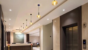 A modern hotel lobby with a reception desk, a staircase leading to an elevator, and pendant lighting. - Hotel Kingsway Continental Raipur (Raipur)