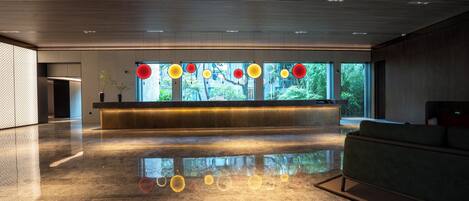 A modern reception area with a polished floor, a reception desk, and large windows offering a view of greenery.