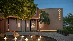 A modern hotel exterior with a water feature in the foreground and illuminated signage.
