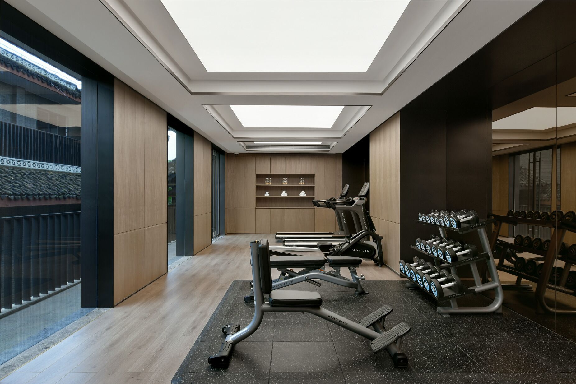 A modern gym with a skylight, exercise equipment, and a weight rack.