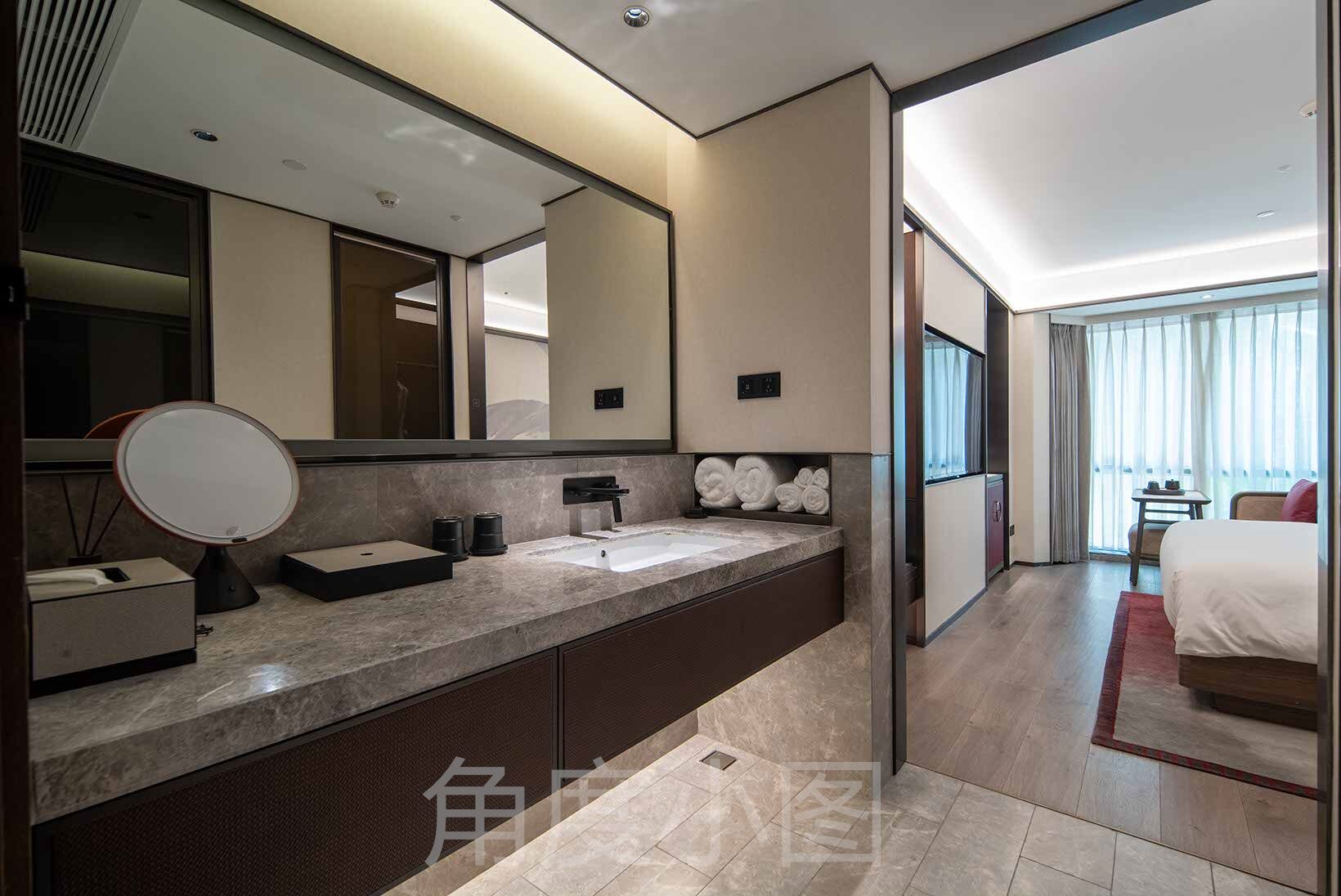 Un baño de hotel moderno con un espejo grande, un lavabo y un perchero para toallas.