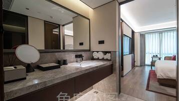 Un baño de hotel moderno con un espejo grande, un lavabo y un perchero para toallas.