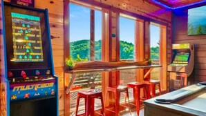 Un intérieur en bois agrémenté de jeux d’arcade, d’un espace bar et de grandes fenêtres donnant sur un espace verdoyant.
