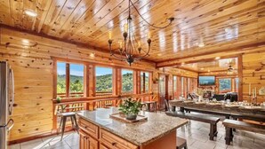 Une cuisine spacieuse aux murs en bois, dotée d’un grand îlot central et d’un coin repas avec des bancs.