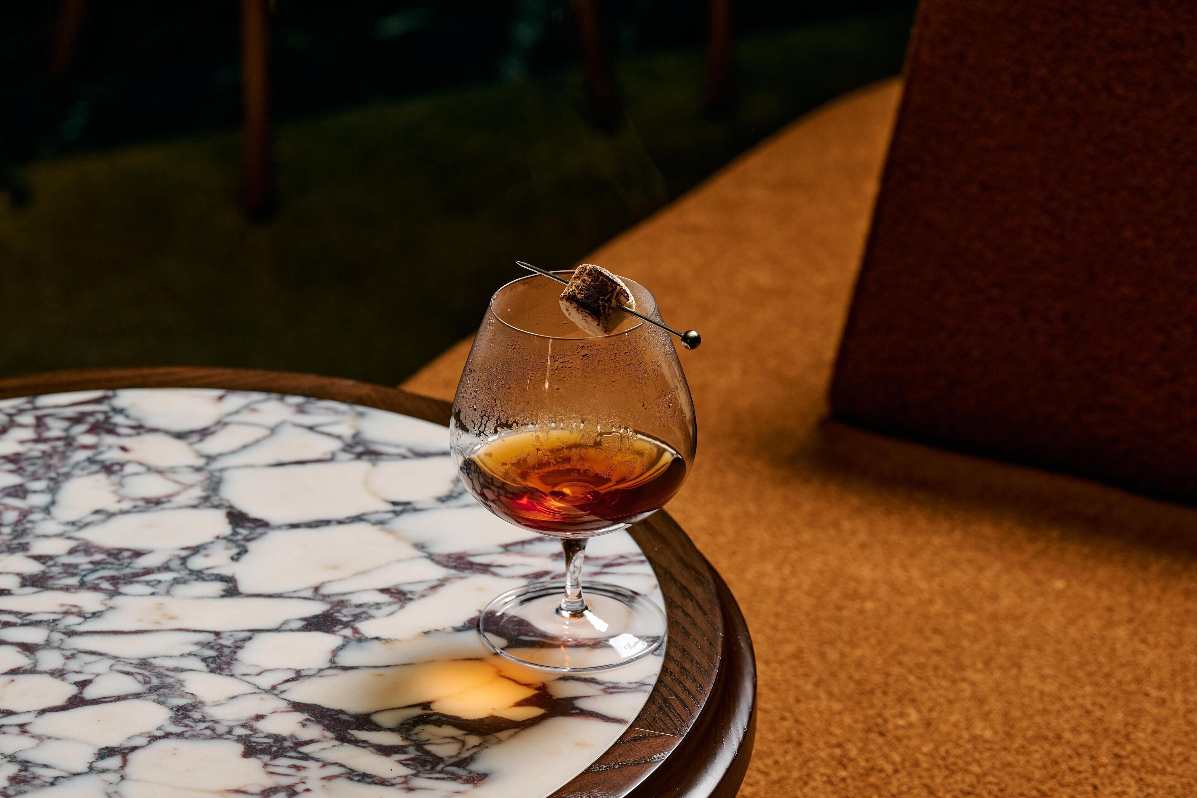 Een glas rode wijn op een marmeren tafel met een kaars.