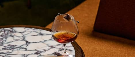 A glass of red wine on a marble table with a candle.