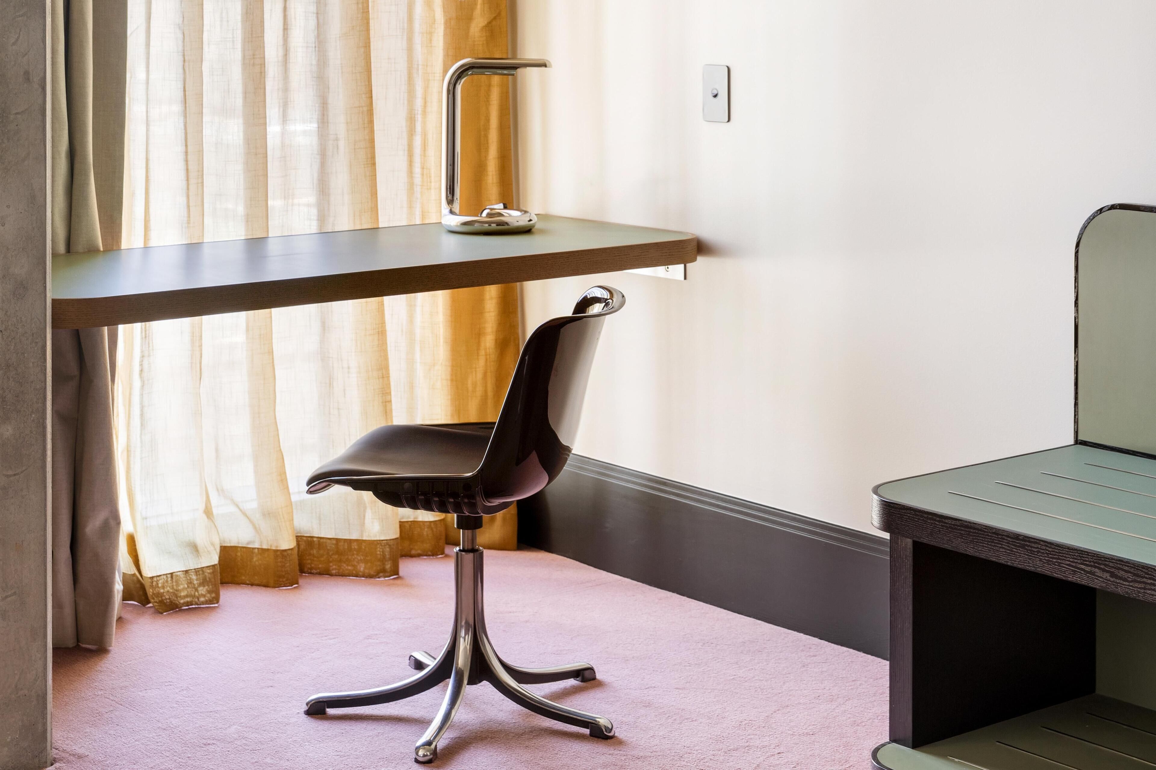 A room with a desk, chair, and a small table.