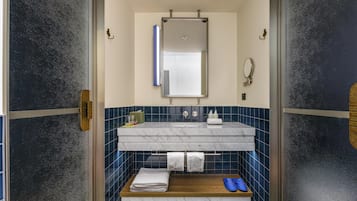 A bathroom with a glass door, a marble sink, a mirror, and a towel rack.