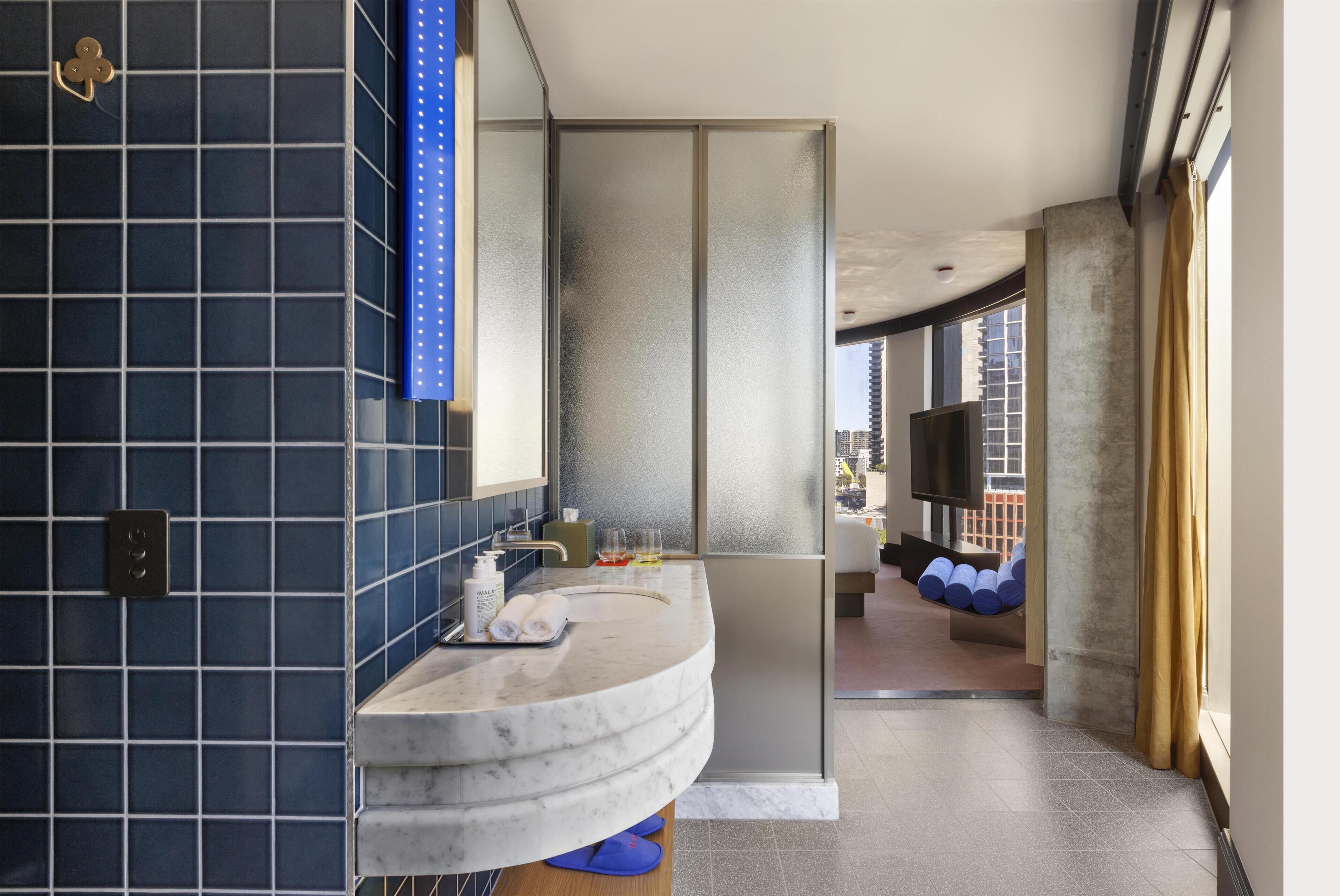 A modern bathroom with a curved marble sink, a large mirror, and a view of the city through a large window.