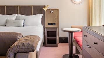 A hotel room with a bed, bedside table, lamp, and a small round table.