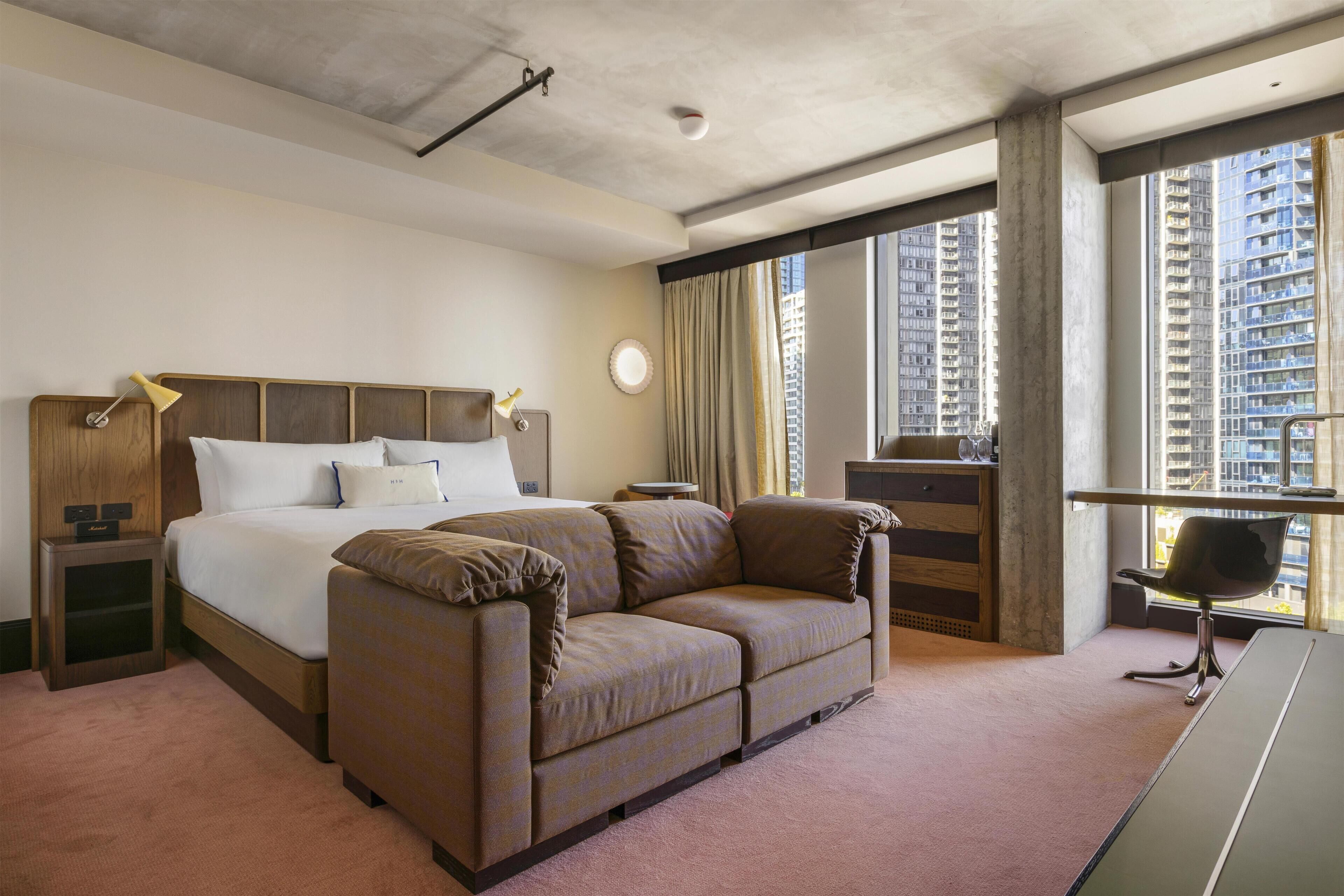 A hotel room with a bed, a sofa, a desk, and a chair.