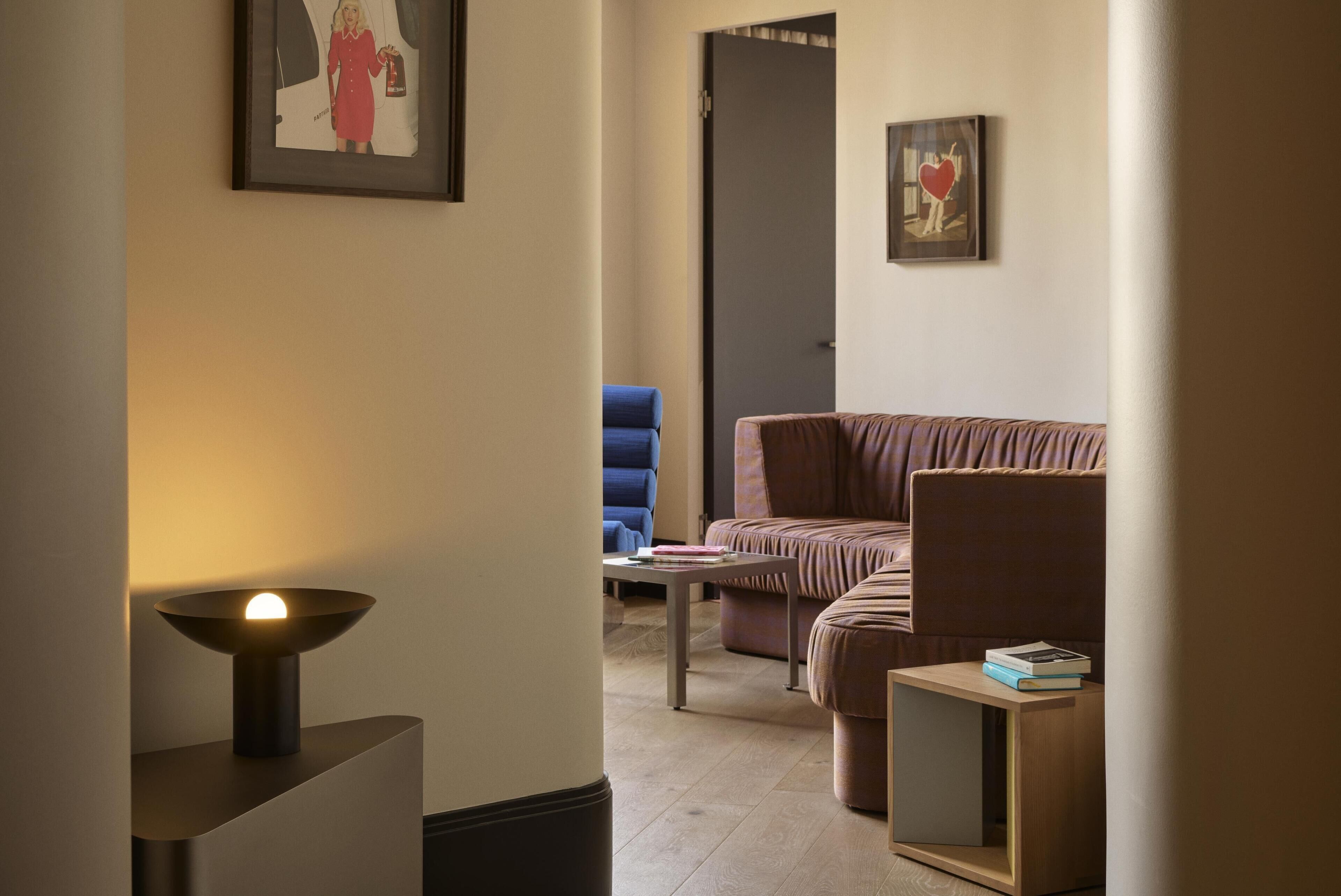 A modern living room with a sofa, a blue armchair, a small table, and a floor lamp.