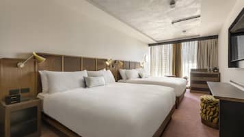 A hotel room with two beds, a desk, a chair, a lamp, and a window with curtains.