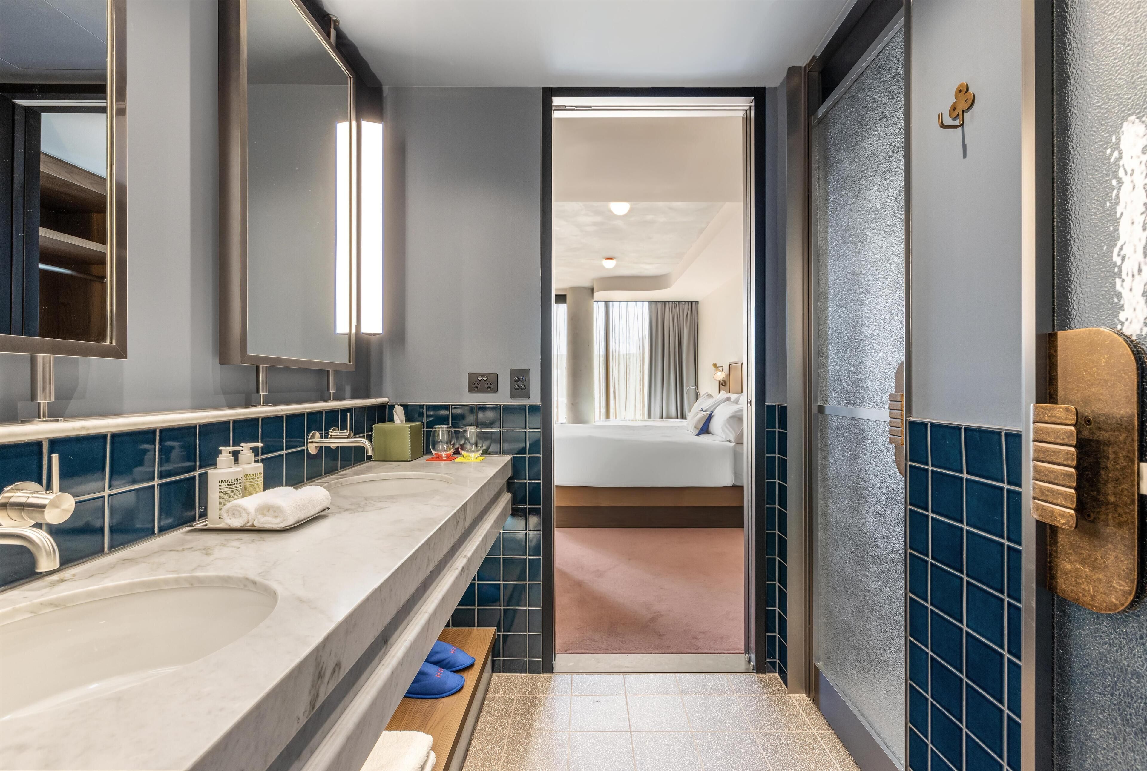 A modern bathroom with dual sinks, a mirror, and a shower area.