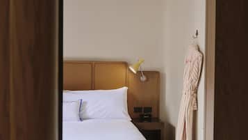 A hotel room with a bed, a bedside lamp, a nightstand, and a robe hanging on a hook.