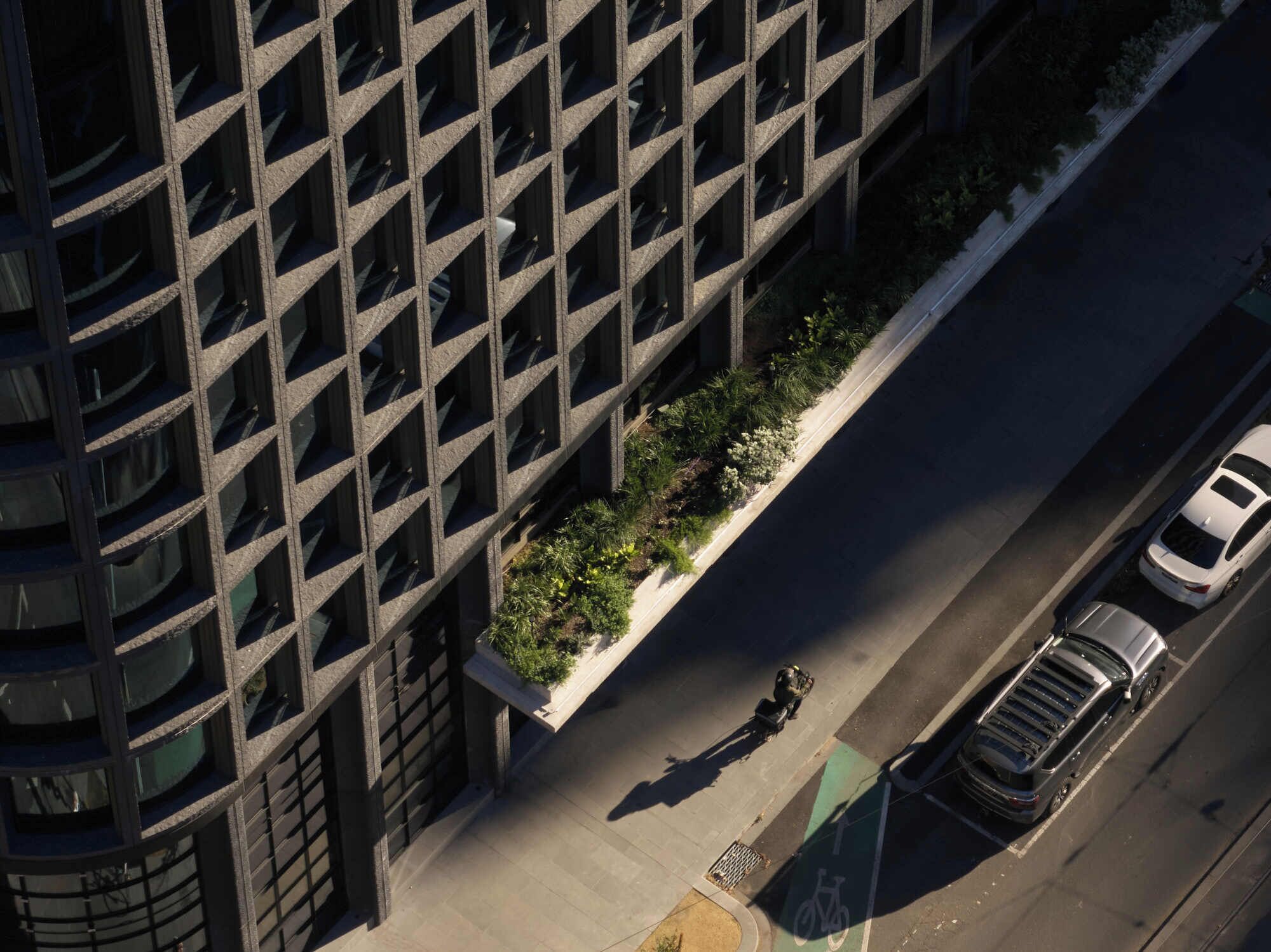 An aerial view of a building with a grid of windows and a landscaped area with plants.
