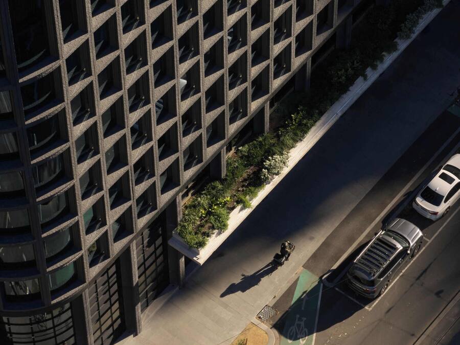 An aerial view of a building with a grid of windows and a landscaped area with plants.