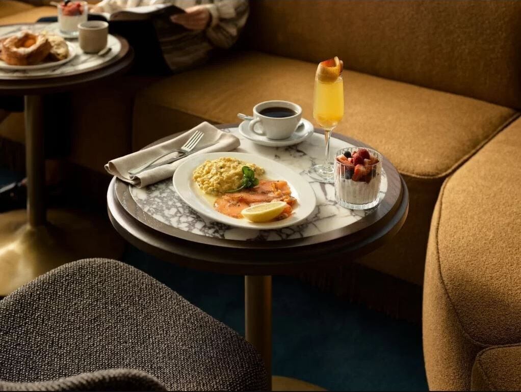 Et spisebord med morgenmad, en kop kaffe og et glas appelsinjuice.