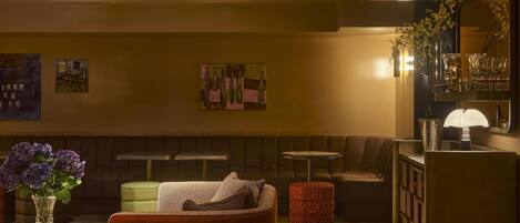 A modern living room with a sofa, a coffee table, a patterned rug, and a bar area with glasses and a vase.