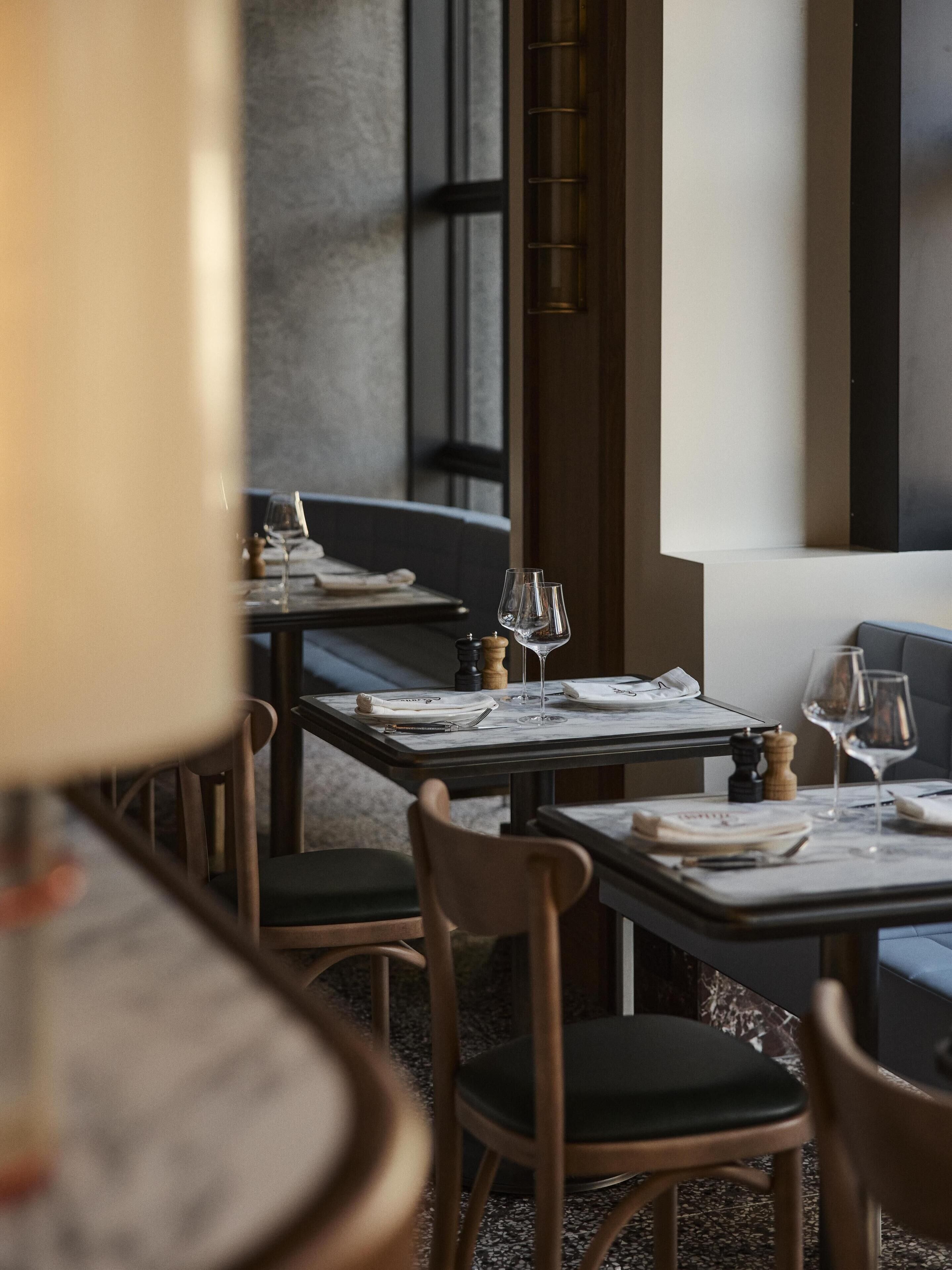 A restaurant interior with tables set for dining, chairs, and a bar area.