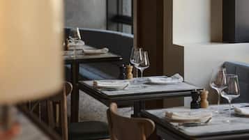 A restaurant interior with tables set for dining, chairs, and a bar area.