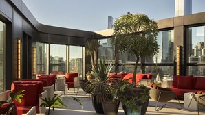 A modern rooftop lounge with seating, potted plants, and a city view. - Hannah St Hotel Melbourne (Southbank)