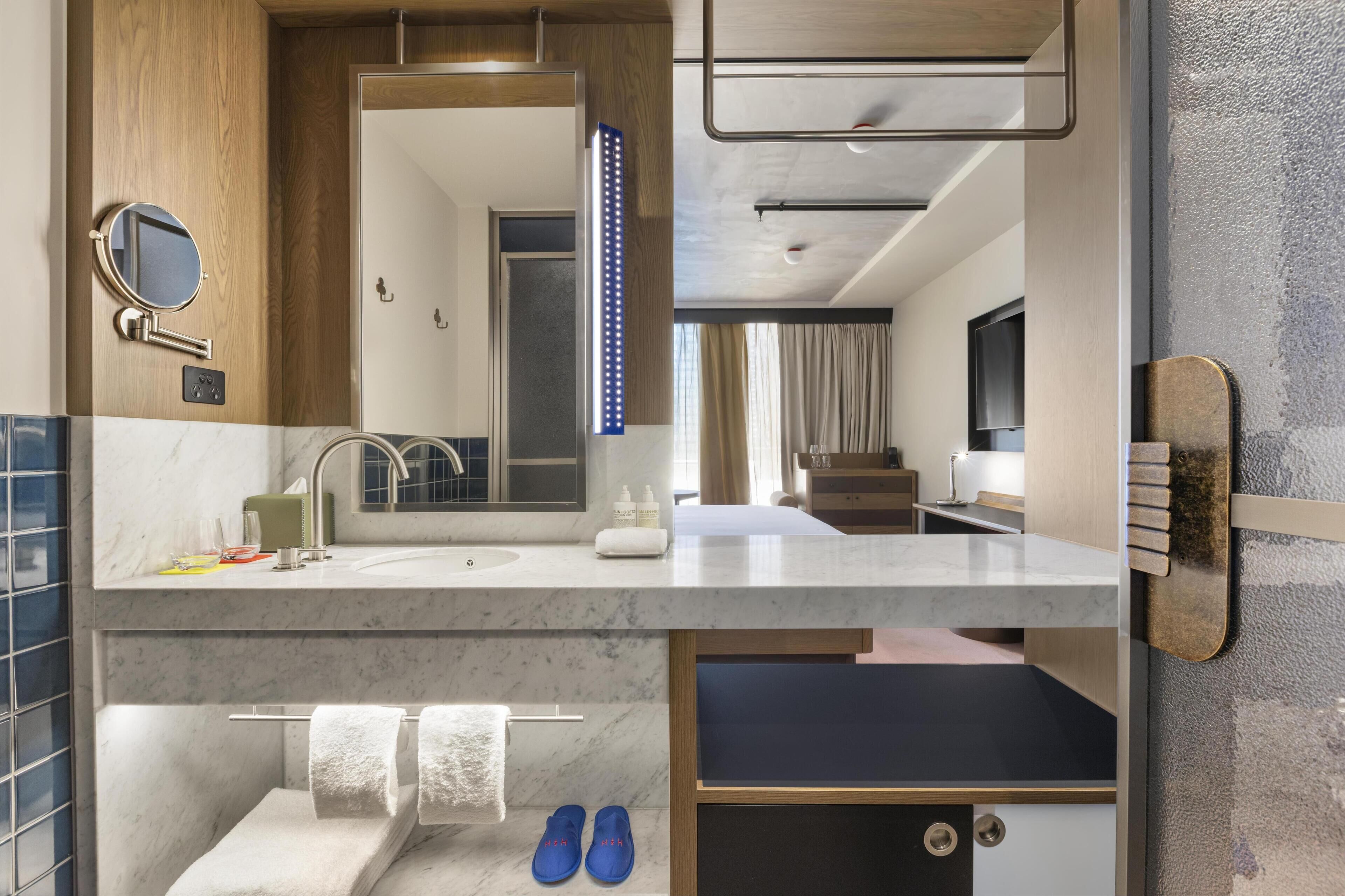 A modern bathroom with a vanity, mirror, and towel rack.