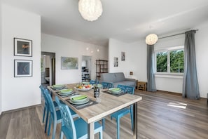 A modern dining area with a wooden table, blue chairs, and a view of a kitchen and living room. - Casa Tramonti: Mountain-View with Terrace Dining, Gemonio, Italy (Gemonio)