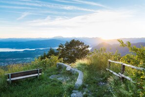 Un banc placé face à un paysage montagneux, offrant une vue sur des montagnes lointaines et un lac.