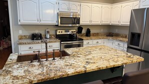 A kitchen with white cabinets, stainless steel appliances, and a granite countertop.