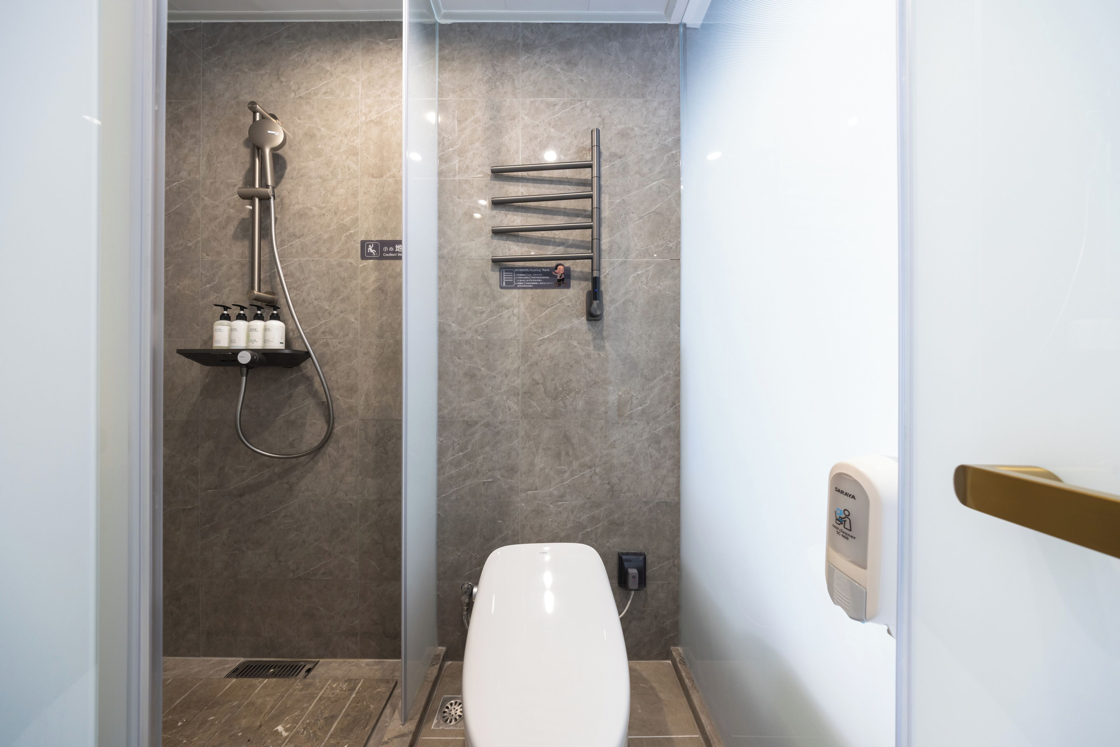 Un baño moderno con ducha, inodoro y toallero.