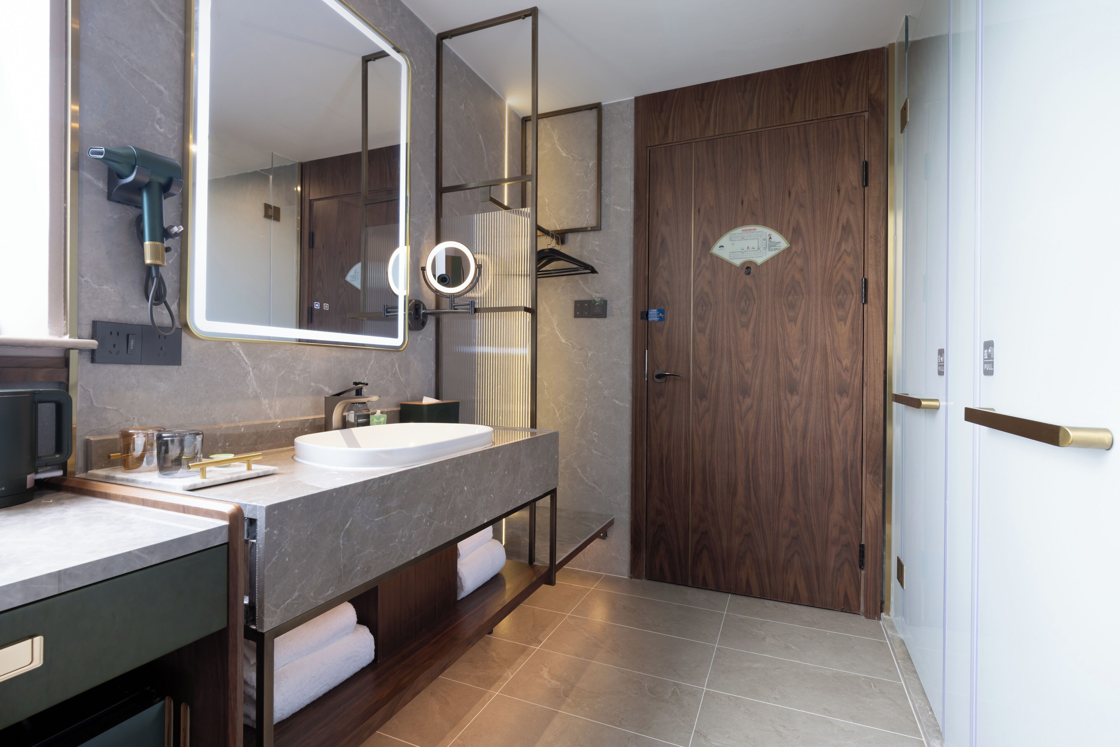 Un baño moderno con un espejo grande, lavamanos dobles y una puerta de madera.