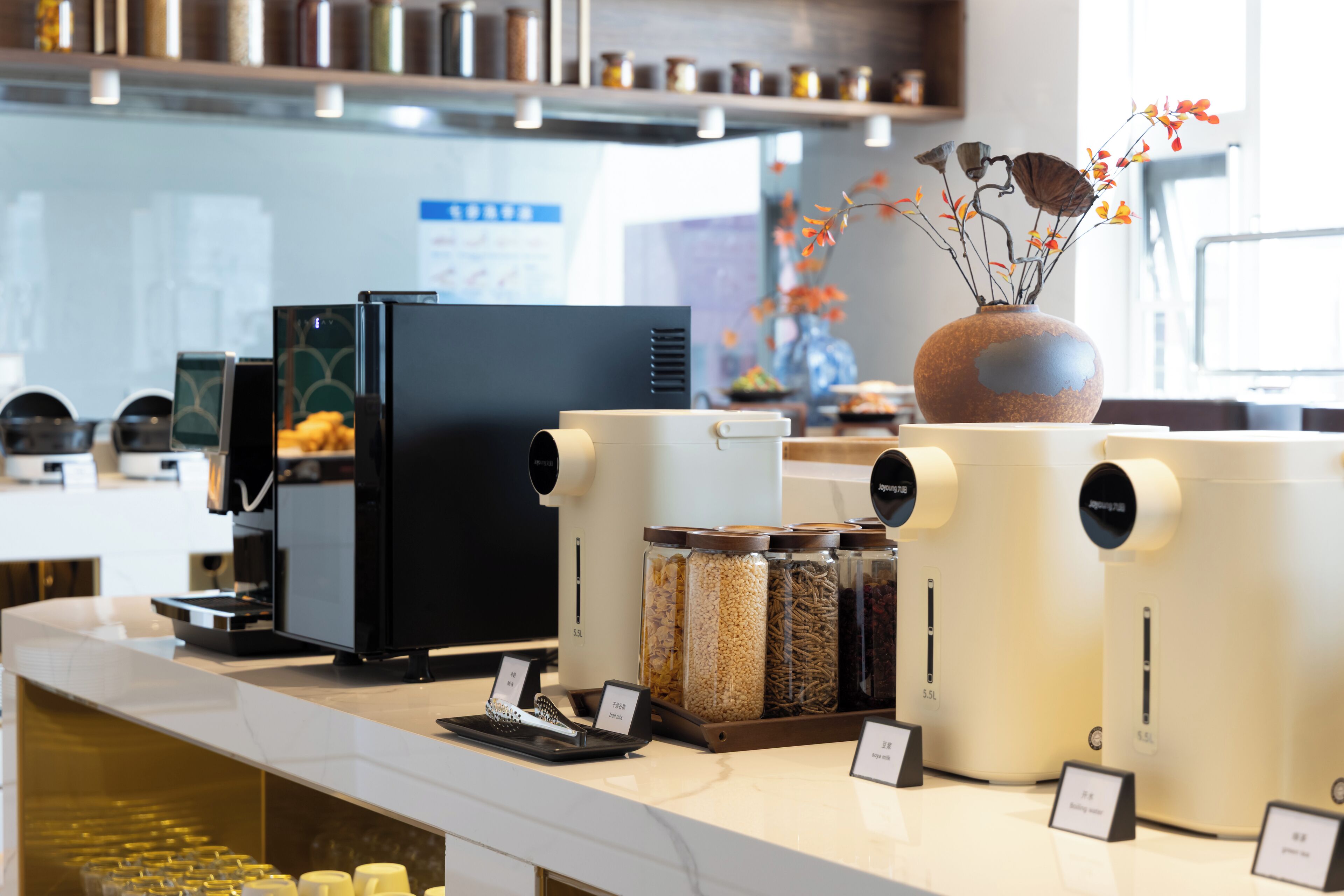 Un espace dédié au café, équipé de plusieurs machines à café, où sont exposés différents types de grains de café, et agrémenté d’un vase rempli de fleurs.