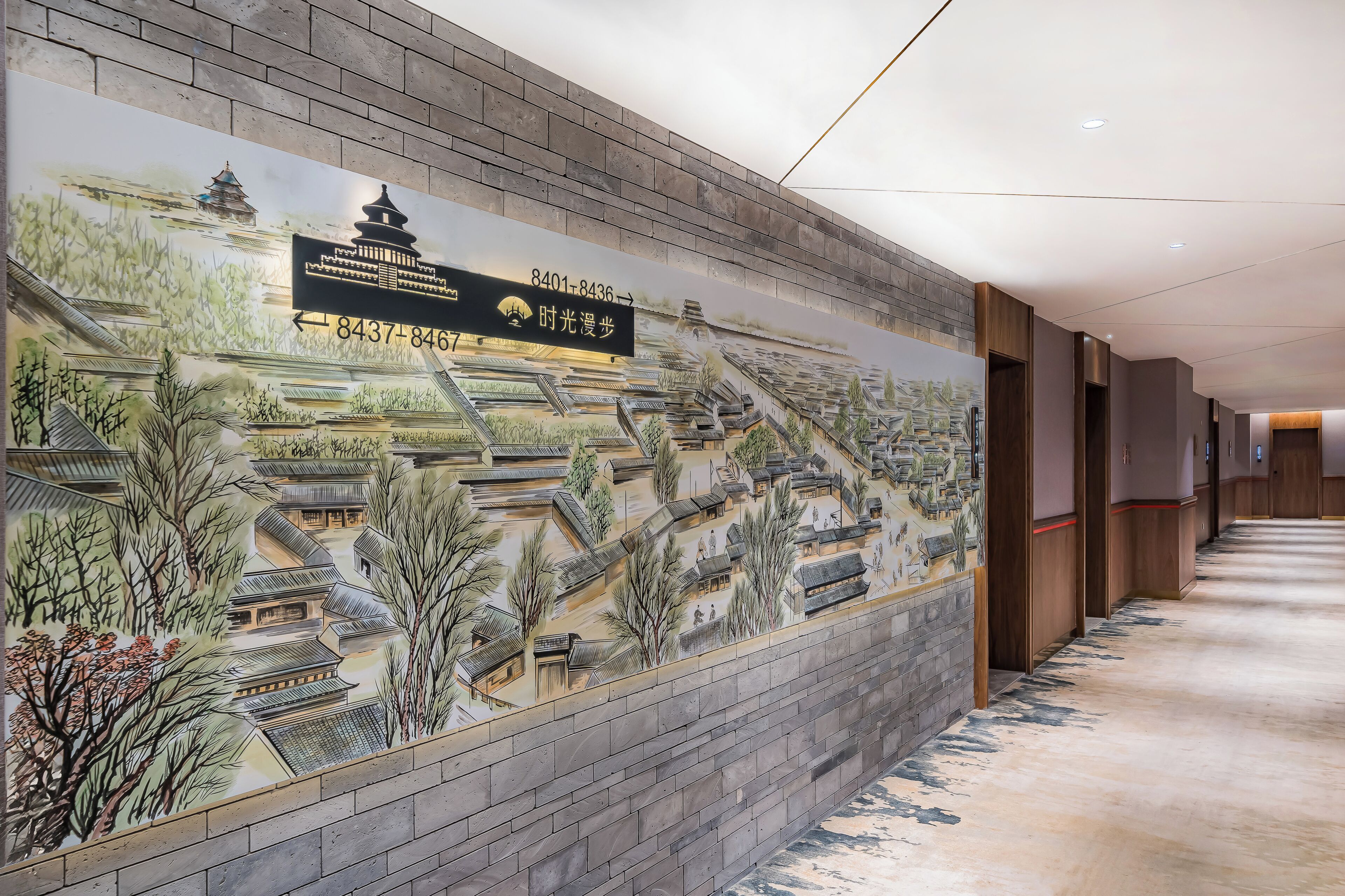 Un pasillo con un mural que representa la arquitectura tradicional y un letrero con información de contacto.