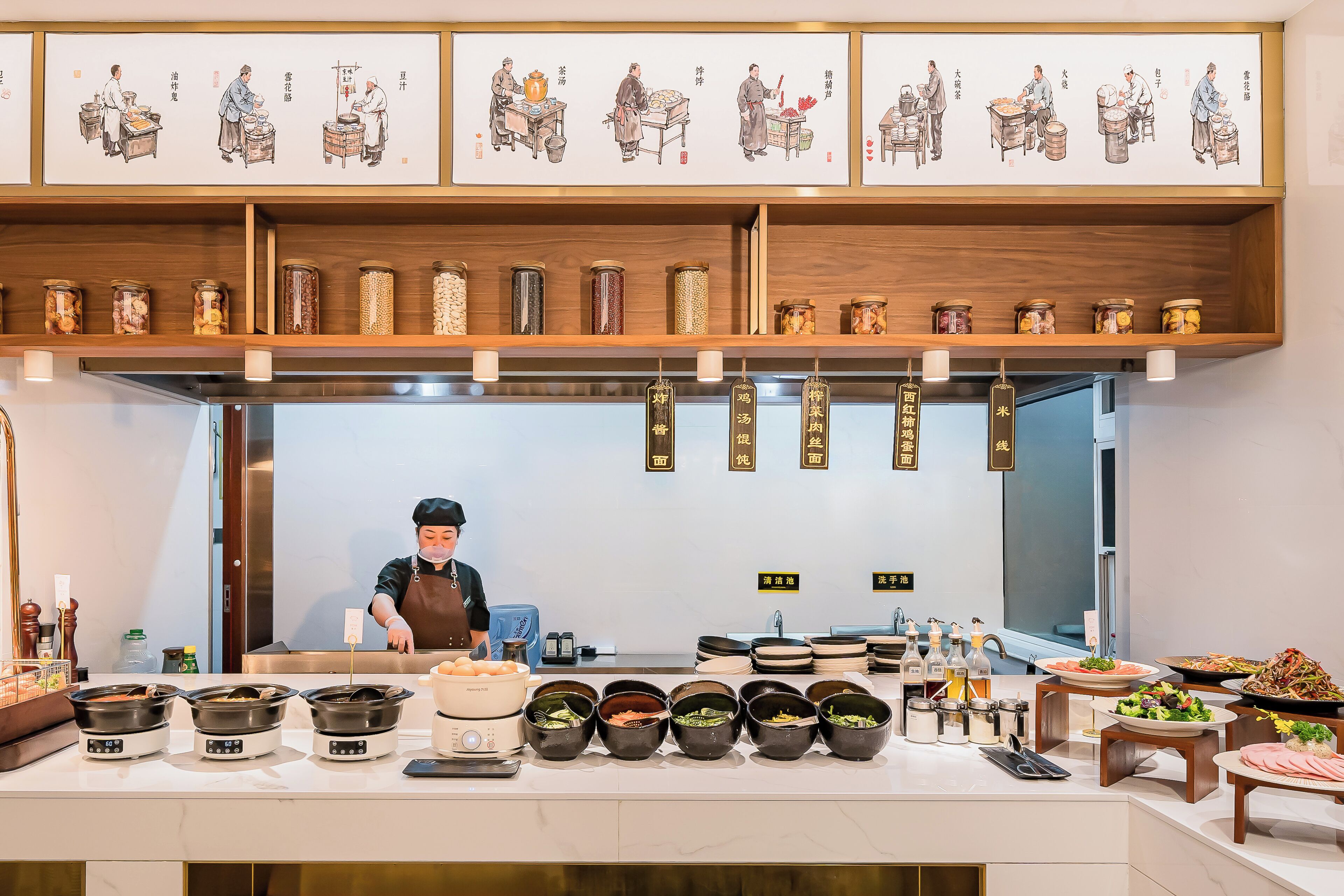A restaurant with a chef preparing food, various dishes displayed, and traditional artwork on the walls.
