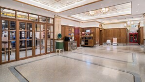Tilava aula, jossa on korkea katto, puupanelointi ja keskeisellä paikalla sijaitseva vastaanottotiski.
