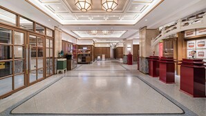 Un vestíbulo de hotel con piso pulido, mostrador de recepción de madera y una exhibición de jaulas de pájaros.