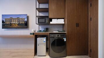 Une chambre d’hôtel compacte équipée d’un lave-linge et d’un sèche-linge intégrés, d’un four à micro-ondes et d’un petit réfrigérateur.