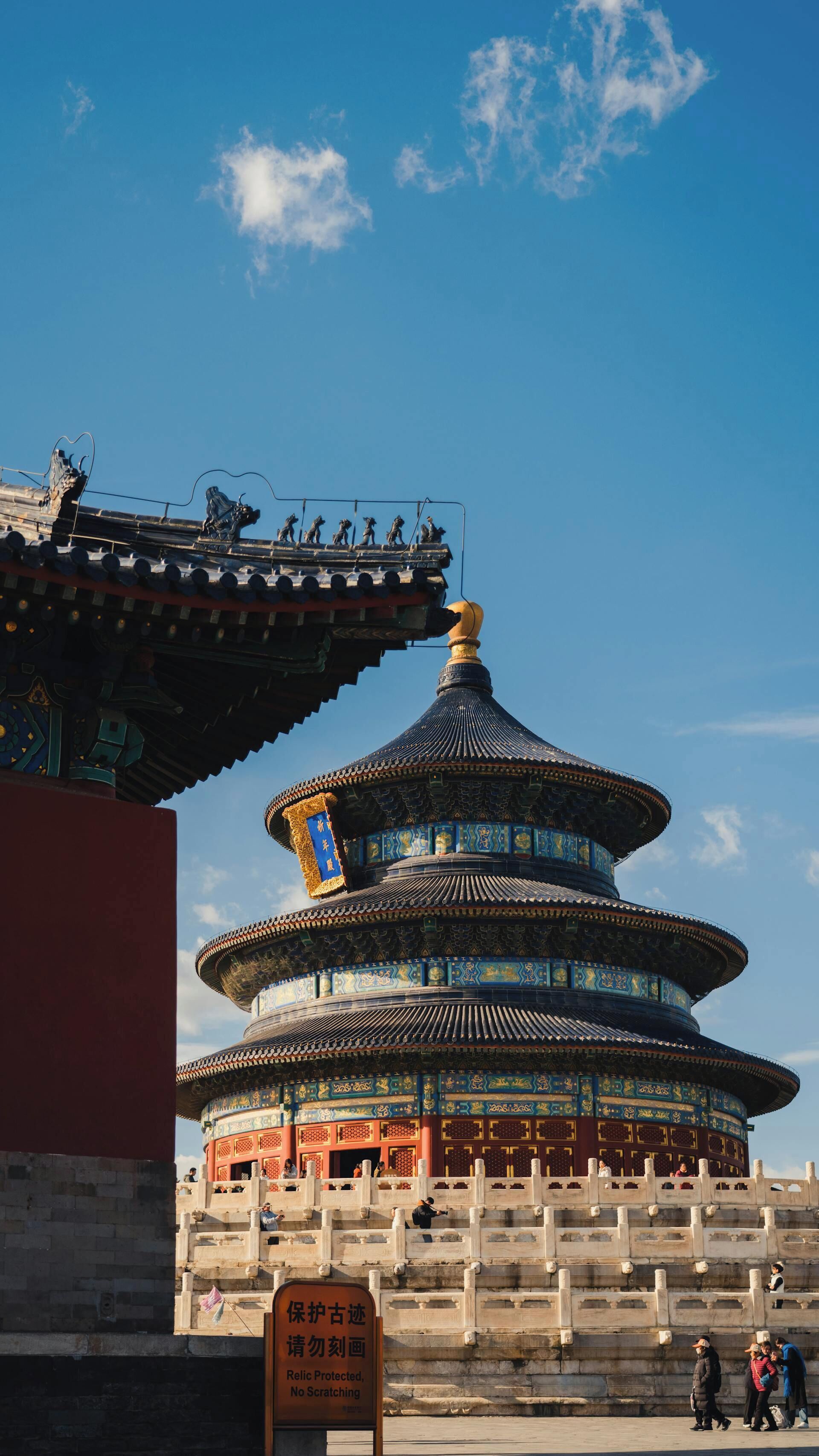 A traditional multi-tiered pagoda with intricate roof designs and a sign indicating protection against defacement.