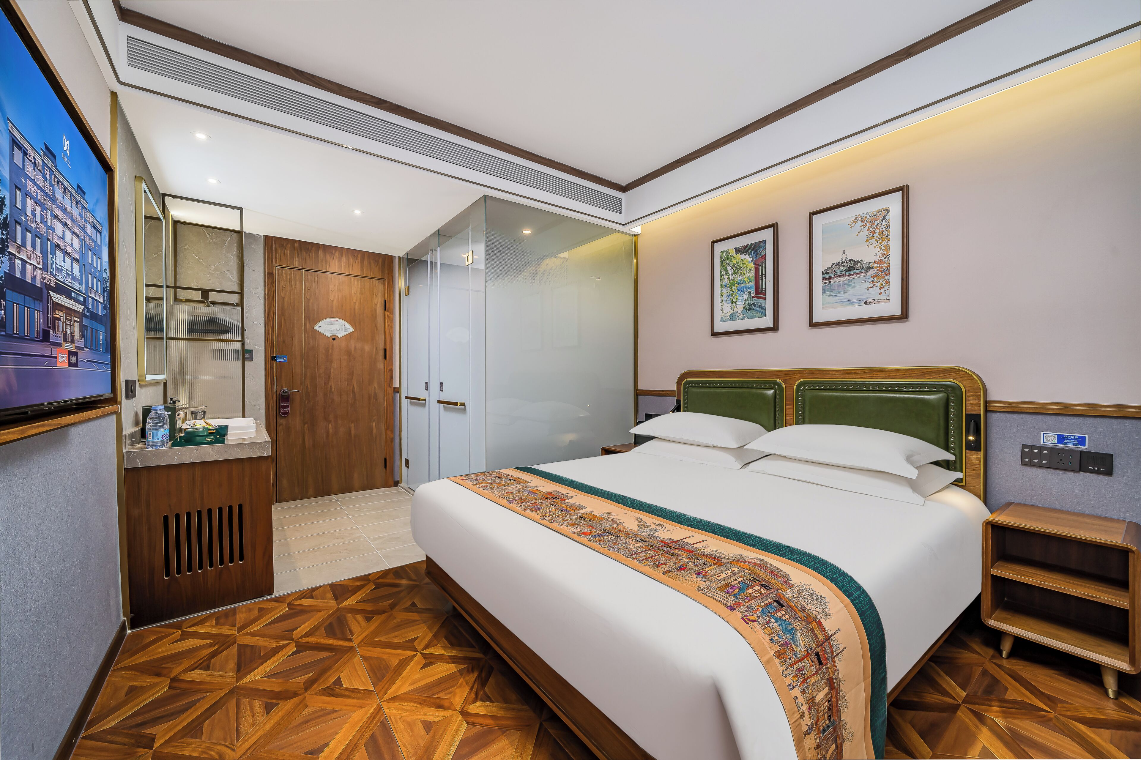 Habitación de hotel con cama, tocador, espejo, puerta y televisor montado en la pared.