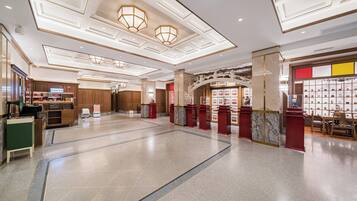 A spacious lobby with a high ceiling, recessed lighting, and a central staircase.